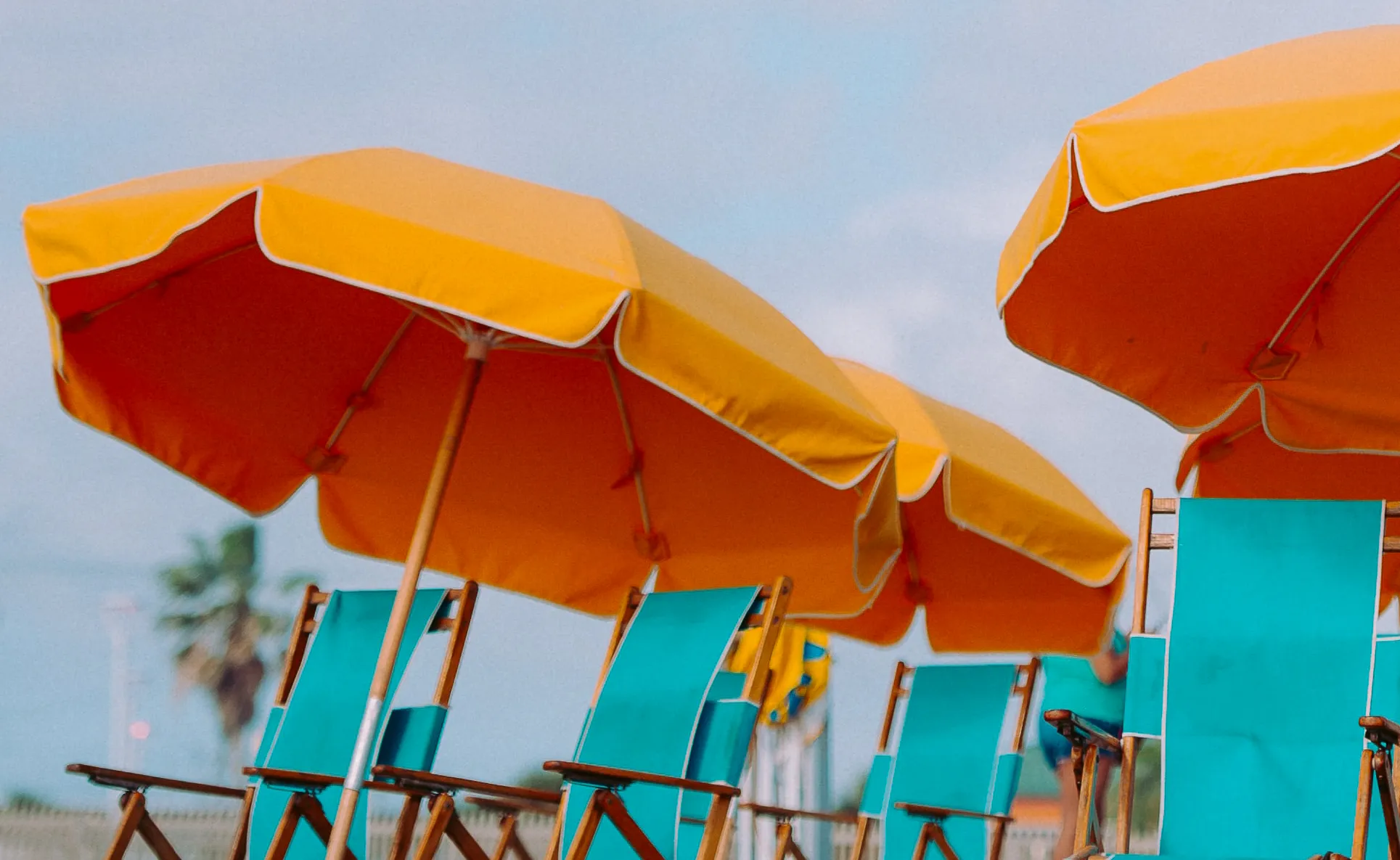 Orange beach umbrellas over blue beach chairs